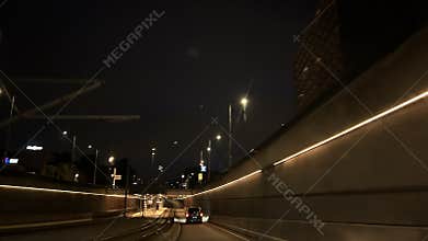 Nighttime car driving through illuminated urban tunnel with curving roadway