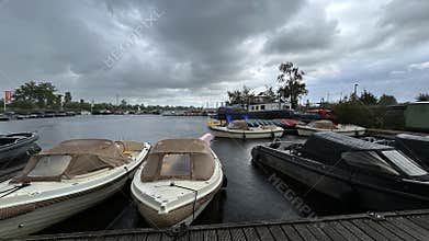 Rainy marina with moored leisure boats on calm water under heavy storm