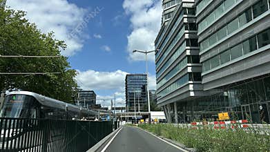 Modern office building and tram at urban street with blue sky and