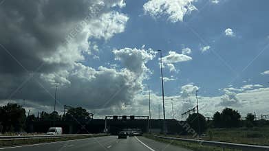Dramatic highway view with dark storm cloud over open roadway, moving cars
