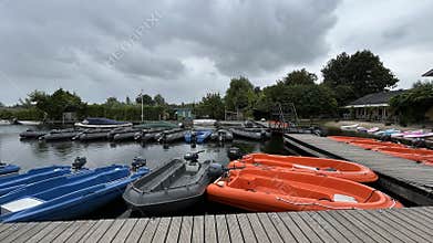Moored small boats and motor dinghies beside wooden docks on calm water