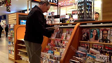 Close up man choosing magazine to buy at newspaper booth