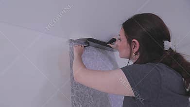 Trimming wallpaper in the corners of a room after wallpapering. Trimming excess paper.