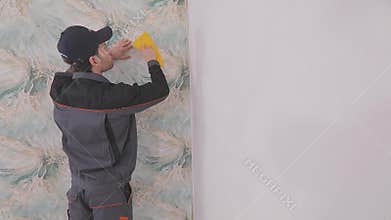 Trimming wallpaper in the corners of a room after wallpapering. Trimming excess paper.