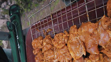 Hand Placing Raw Marinated Chicken Pieces Onto a Metal Grill Grate