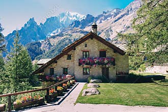 Beautiful old house with flowers in Courmayeur, Italy, over panoramic view of Mont Blanc