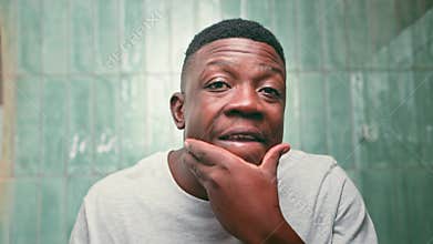 Happy Black Man Engaging in Morning Skincare and Hygiene Routine in Bathroom