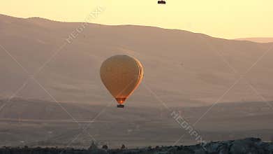 Hot air balloons drift above Cappadocia fairy chimneys and volcanic valleys at sunrise, sky, balloon panorama, dawn light, turkiye