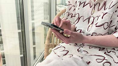 Person using smartphone near a window in a bright apartment