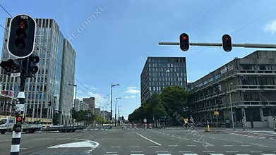 Modern urban intersection with red traffic lights, glass office towers, tram