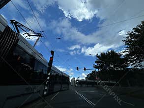 Urban tram crossing under overhead cables at red traffic lights on wide