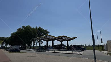 Modern roadside parking area with solar canopy, cars, trees, open rural landscape