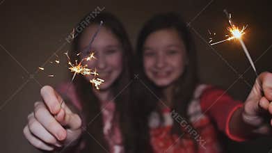 Two teen girls posing and smiling lit sparklers