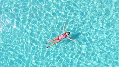 Aerial spinning view of an attractive woman floating in crystal clear sea