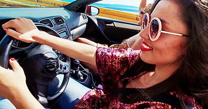 Attractive woman turning steering wheel driving friends convertible car, graded