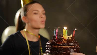 Pretty Lady in Cap is Blowing out Her Birthday Candles on Chocolate Cake and Applauding. Woman with Charming Smile on