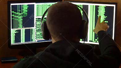 Hacker is looked to binary code. Criminal hacker penetrating network system from his dark hacker room. Hacker stealing