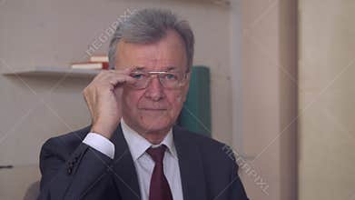 Aged leader posing indoors.