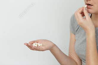 Women are taking capsules on white background.