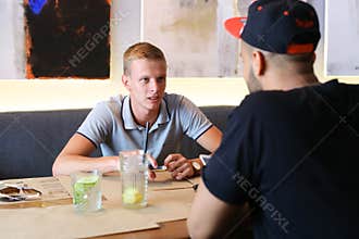 Male friends in cafe talk discuss with technology phone tablet