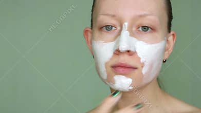 Woman doing cosmetic mask on her face
