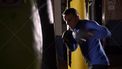 Boxer hits punching bag. The sports man beats a punching bag. The man in the gym. The trainer plays sports. Punching bag