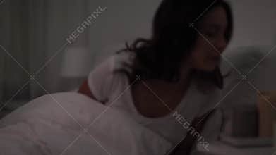 Woman in bed blowing candles and going to sleep