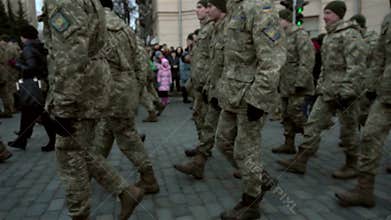 Formation of soldiers in uniform marching on the pavement on the street