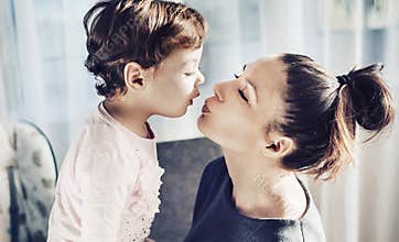 Portrait of a mother kissing her beloved child