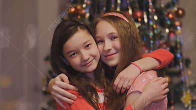 Girls teens hugging smiling on the background of Christmas tree