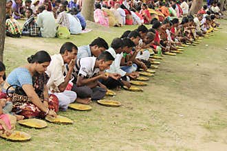 People are eating in a row during Bengali cultural festival.
