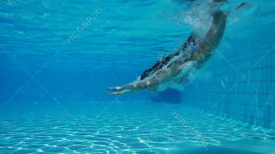 Girl jump in swimming pool and swim underwater