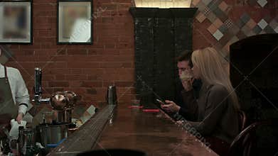 Young cheerful friends drinking cocktails and talking with barman in lounge disco bar