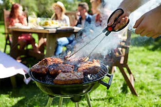 Man cooking meat on barbecue grill at summer party