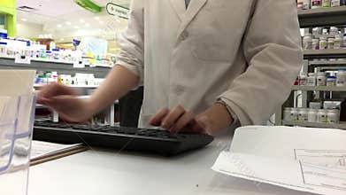 Pharmacy assistant typing customer information for prescription medicine