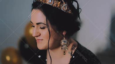 Brightful party event of joyful young women in elegant black dress and yellow crown celebrating new year, birthday