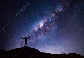 Milky Way landscape. Silhouette of Happy man standing on top of mountain with night sky and bright star on background
