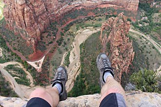 First person perspective shot from a hiker sitting at the edge of a cliff in Zion National Park.