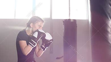 Teen girl in boxing gloves is working out a blow. Slow motion