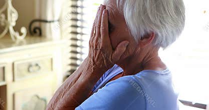 Stressed senior woman covering her face with hands