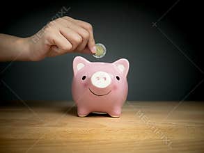 Hand add coin to piggy bank save coin, time and money concept