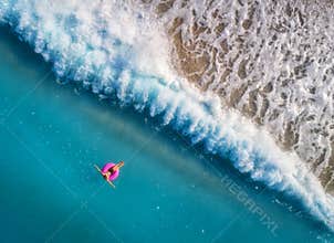 Aerial view of young woman swimming on the pink swim ring