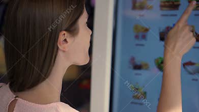 Beautiful attractive woman in mall. Ordering food via self-service machine at fast-food chain restaurant