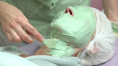 Cosmetician applying alginate facial mask.