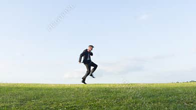 Crazy businessman dancing on a hill