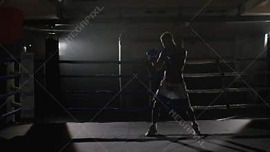 Kickbox fighter shadow boxing in the ring. The athlete fights with his shadow. Young boxer in training throwing a punch