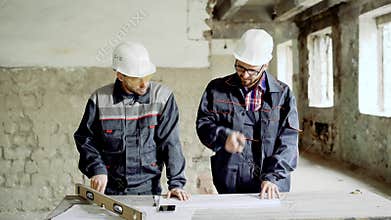 Two professional engineers working together at the desk with building documentation on construction area.