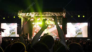 People clap their hands, night rock concert in open air, slow motion many lights on stage