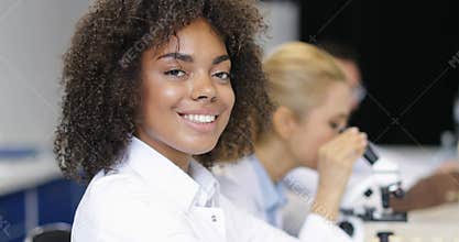 African American Female Scientist Over Colleagues Specialists Working With Microscope Making Chemical Experiments