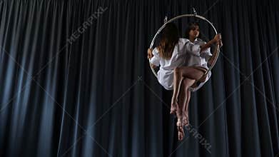 Young girls is spinning in the aerial hoop